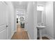 Bright hallway featuring wood-look floors, a half bathroom with pedestal sink, and entry to the modern kitchen at 2806 High Plains Dr, Fuquay Varina, NC 27526