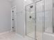 Modern shower with glass doors and white marble tile surround, next to doorway with towel bar at 2914 Farmhouse Dr, Apex, NC 27502