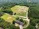 Expansive aerial view showcasing the property, including the house, stables, riding arena, and lush surroundings at 3129 Tarheel Clubhouse Road Rd, Raleigh, NC 27604