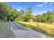 Welcoming home with a long driveway, chain link fence, and lush green lawn under a sunny sky at 3129 Tarheel Clubhouse Road Rd, Raleigh, NC 27604