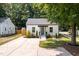 A quaint white home with green door, complemented by a concrete driveway and landscaped front yard at 3649 Guess Rd, Durham, NC 27705