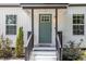 An inviting porch and green door with white trim, enhanced by the neat landscaping and black railing at 3649 Guess Rd, Durham, NC 27705