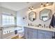 Elegant bathroom showcasing double sinks, hexagon mirrors, a soaking tub, and natural light at 418 Magna Dr, Durham, NC 27703