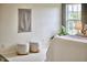 Bright bedroom featuring neutral walls, two cushioned ottomans, and natural light from the window at 418 Magna Dr, Durham, NC 27703