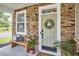 Inviting front porch with stone accents, a decorative wreath on the door, and a wooden bench with stylish pillows at 418 Magna Dr, Durham, NC 27703