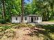 Charming single-story home featuring white siding, a black door and trim, and mature trees surrounding the property at 4428 W West River Rd, Franklinton, NC 27525
