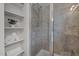 Tiled shower with glass door, built-in shelves with towels and decorative plant at 444 Claremont Dr, Chapel Hill, NC 27516