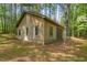 View of the rear exterior of a wood sided outbuilding surrounded by a pine needle floor at 4501 Zebulon Rd, Zebulon, NC 27597