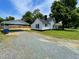 Exterior view of a white home with a detached carport, gravel driveway, and well-maintained lawn at 510 May St, Gibsonville, NC 27249