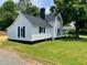 Side view of a charming home featuring white siding, black shutters, a chimney, and a well-kept lawn at 510 May St, Gibsonville, NC 27249