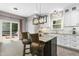 Open-concept kitchen features an island, white cabinets, modern lighting, and sliding doors leading to an outdoor deck at 5301 Denmead Way, Raleigh, NC 27613