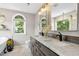 Bright bathroom featuring a double vanity with marble countertops, an arched window, and a soaking tub at 5301 Denmead Way, Raleigh, NC 27613
