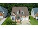 An aerial view of a brick home featuring a two-car garage, manicured lawn and mature trees at 5818 Myakka Ct, Raleigh, NC 27616