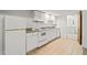 Basement kitchenette with white appliances, white cabinets, and tile flooring; simple and elegant at 601 Wofford Rd, Durham, NC 27707