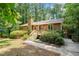 Charming home with a wooden porch and stairs surrounded by lush greenery and mature trees at 601 Wofford Rd, Durham, NC 27707