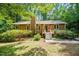Charming single-story home with wood siding and a cozy front porch surrounded by mature trees and lush landscaping at 601 Wofford Rd, Durham, NC 27707