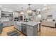 Open gourmet kitchen with stainless appliances, marble countertops, large island with sink, and hardwood floors at 602 Preston Village Way, Cary, NC 27519