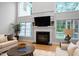 Living room featuring large fireplace, tall windows, hardwood flooring, and lots of natural light at 602 Preston Village Way, Cary, NC 27519