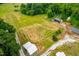 Expansive aerial view showing cleared land, outbuildings, and surrounding lush greenery at 6318 Hurdle Mills Rd, Roxboro, NC 27574
