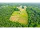 Lush aerial landscape showing forest surrounding a sizable cleared property with space for farming at 6318 Hurdle Mills Rd, Roxboro, NC 27574