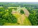 Extensive aerial view displaying cleared land, outbuildings, a residence, and wooded areas at 6318 Hurdle Mills Rd, Roxboro, NC 27574