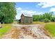 Rustic barn with a metal roof stands at a crossroads in the gravel driveway, with ample space at 6318 Hurdle Mills Rd, Roxboro, NC 27574