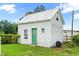 Quaint outbuilding with green door and white siding, set in a lush, grassy area with fencing at 6318 Hurdle Mills Rd, Roxboro, NC 27574