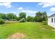 Expansive lawn dotted with outbuildings and barns, enhanced by mature trees and a blue sky at 6318 Hurdle Mills Rd, Roxboro, NC 27574