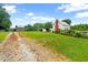 View of the property showing a gravel driveway leading to a small building with a red brick chimney at 6318 Hurdle Mills Rd, Roxboro, NC 27574