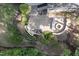 Aerial view of a backyard with stone patio, grill area, fire pit, lush landscaping, and trees at 633 Rolling Springs Dr, Cary, NC 27519