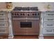 Close-up of a stainless steel Wolf stove with red knobs, marble countertops, and white cabinets in the kitchen at 633 Rolling Springs Dr, Cary, NC 27519