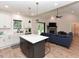 Open kitchen with island, stainless steel appliances, and bar seating flowing into the living room with fireplace at 710 Country Rd, Middlesex, NC 27557