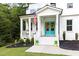 Inviting front porch with American flag, bright blue double doors adorned with wreaths, and colorful potted plants at 720 The Parks Dr, Pittsboro, NC 27312
