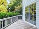 Back deck with wood flooring, white railing, and a sliding glass door overlooking mature trees at 7502 Hedfield Way, Durham, NC 27713