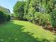 Large backyard features a green lawn surrounded by lush trees and a wooden fence at 7502 Hedfield Way, Durham, NC 27713