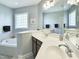 Well-lit bathroom featuring dual sinks, a large mirror, soaking tub, and tiled floor at 7502 Hedfield Way, Durham, NC 27713