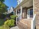 Inviting front porch with brick steps, stone accents, white railing, and well-maintained landscaping at 7502 Hedfield Way, Durham, NC 27713