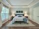 Well-lit main bedroom features a tray ceiling, hardwood floors, and a large window at 7502 Hedfield Way, Durham, NC 27713