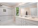 Bright bathroom with double vanity, white tile, and a shower-tub combo featuring decorative tile accents at 7713 Summercrest Dr, Apex, NC 27539