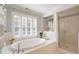 Bright bathroom featuring an oval soaking tub, shuttered windows, and a glass-enclosed shower at 7713 Summercrest Dr, Apex, NC 27539