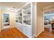 Hallway with custom built-in bookshelves and hardwood floors that lead to a bedroom suite at 7713 Summercrest Dr, Apex, NC 27539