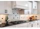 Close-up of gas cooktop, white cabinets and black granite counter with decorative backsplash at 7713 Summercrest Dr, Apex, NC 27539