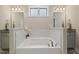 Relaxing bathroom featuring a soaking tub with marble surround, granite countertops and decorative lighting at 824 Stanly House St, Wake Forest, NC 27587