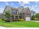 Beautifully landscaped home with a lush lawn, stone accents, and a welcoming two-car garage at 824 Stanly House St, Wake Forest, NC 27587