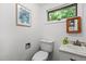 Bathroom with white fixtures, a toilet, sink, and framed artwork, all naturally lit by a window at 908 Cedar Fork Trl, Chapel Hill, NC 27514