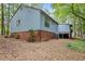 Exterior view of the house showing the siding, crawl space, and a wooded backyard at 908 Cedar Fork Trl, Chapel Hill, NC 27514