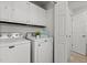 Laundry room with a white washer and dryer, storage cabinets, and an adjacent doorway at 908 Cedar Fork Trl, Chapel Hill, NC 27514