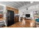 Living room featuring hardwood floors, exposed beams, ceiling fan, and a view of the kitchen area at 908 Cedar Fork Trl, Chapel Hill, NC 27514