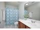 Bright bathroom featuring a vanity with white countertop, framed mirror and tub-shower combo with patterned shower curtain at 979 Branch Line Ln, Apex, NC 27502