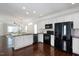 Bright, open kitchen featuring white cabinets, black appliances, granite counters, and wood floors at 979 Branch Line Ln, Apex, NC 27502